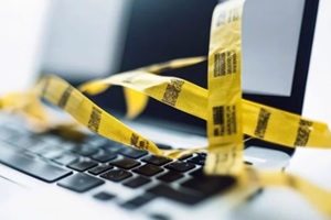 close-up shot of a laptop keyboard entangled in yellow caution tape